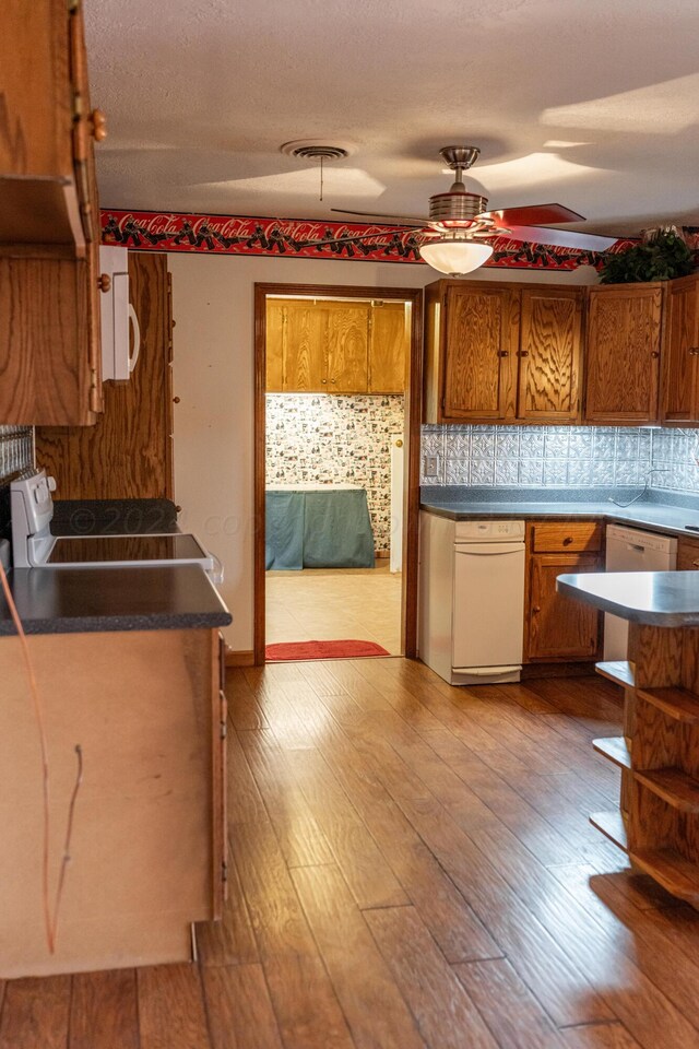 kitchen with light hardwood / wood-style floors, ceiling fan, stove, and backsplash