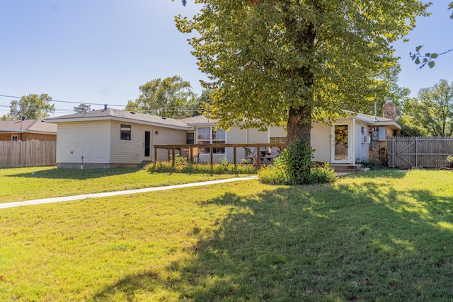 rear view of property featuring a wooden deck and a lawn