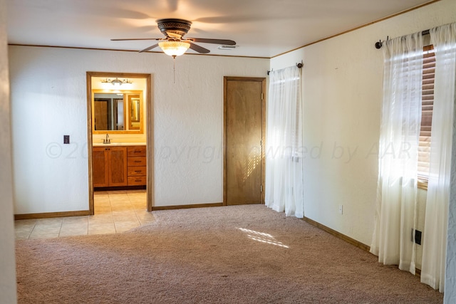 unfurnished bedroom featuring ceiling fan, ensuite bath, light carpet, and sink