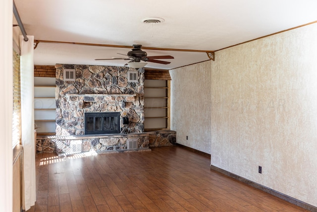 unfurnished living room with wood-type flooring, ceiling fan, crown molding, a fireplace, and built in features