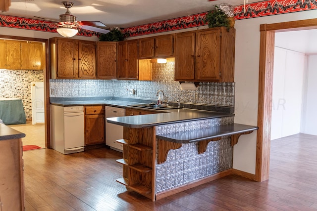 kitchen featuring hardwood / wood-style flooring, tasteful backsplash, sink, stainless steel dishwasher, and ceiling fan