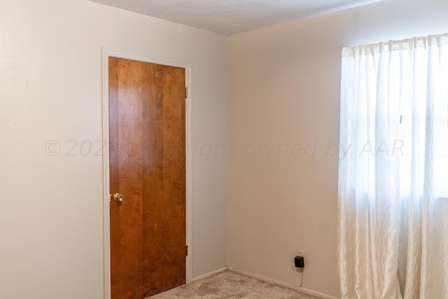 spare room featuring a textured ceiling and light carpet