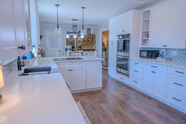 2211 N Aspen Dr, Pampa, TX 79065 - kitchen with black microwave, double oven, wood finished floors, white cabinets, and ornamental molding