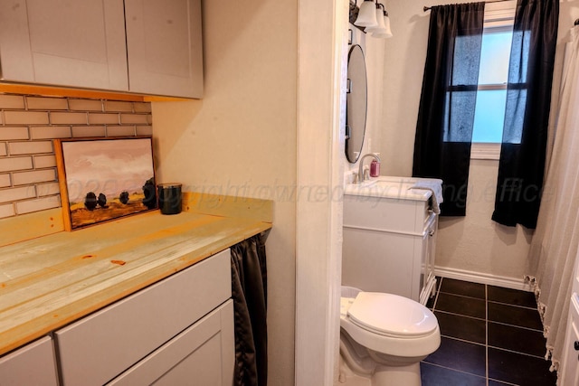 2211 N Aspen Dr, Pampa, TX 79065 - bathroom with vanity, tile patterned flooring, baseboards, toilet, and decorative backsplash
