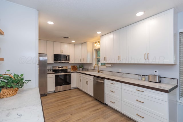 3301 Palmetto Trl, Amarillo, TX 79106 - kitchen with appliances with stainless steel finishes, a sink, white cabinetry, recessed lighting, and light wood-style floors