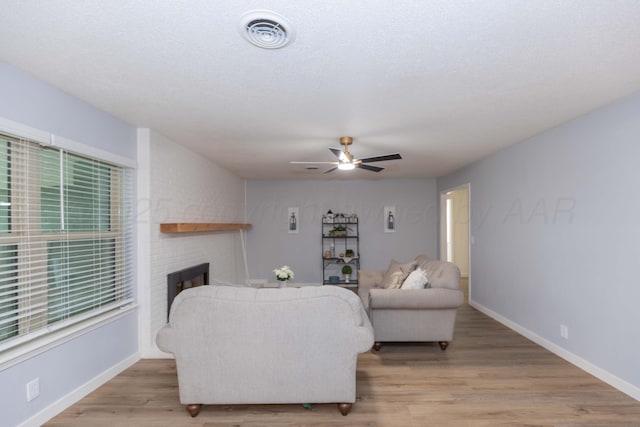 3301 Palmetto Trl, Amarillo, TX 79106 - living room featuring a brick fireplace, ceiling fan, light wood-type flooring, and baseboards
