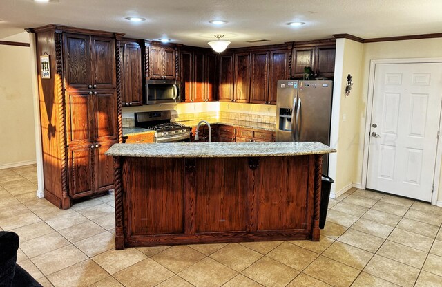 kitchen with crown molding, an island with sink, stainless steel appliances, and light tile patterned floors