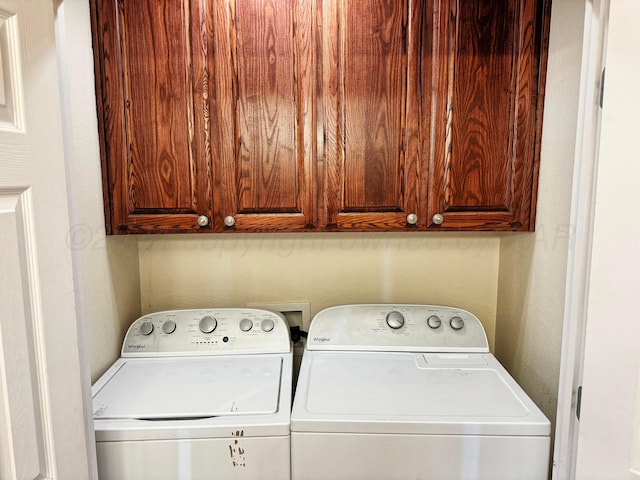 clothes washing area featuring washing machine and clothes dryer and cabinets