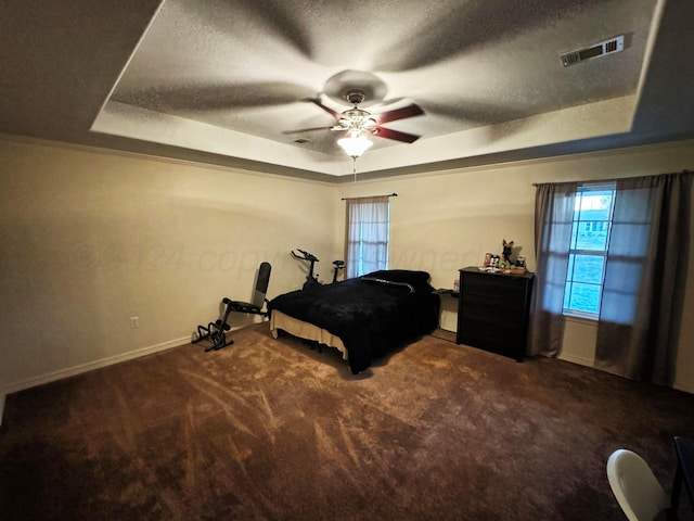 carpeted bedroom with a raised ceiling and ceiling fan