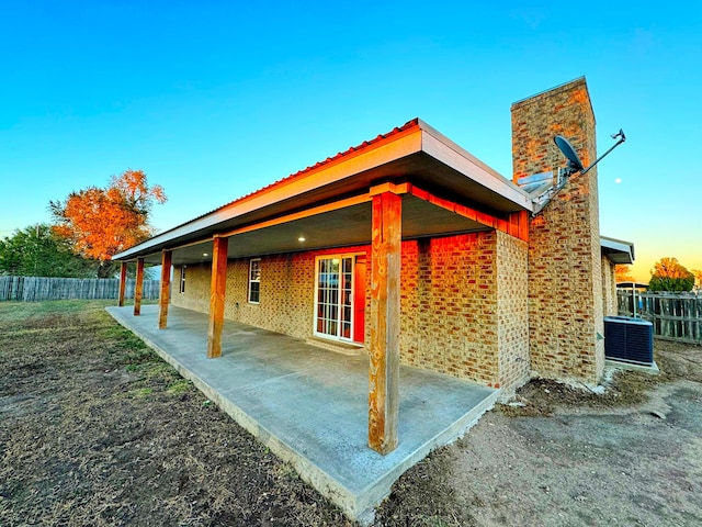 back house at dusk featuring a patio area and central air condition unit