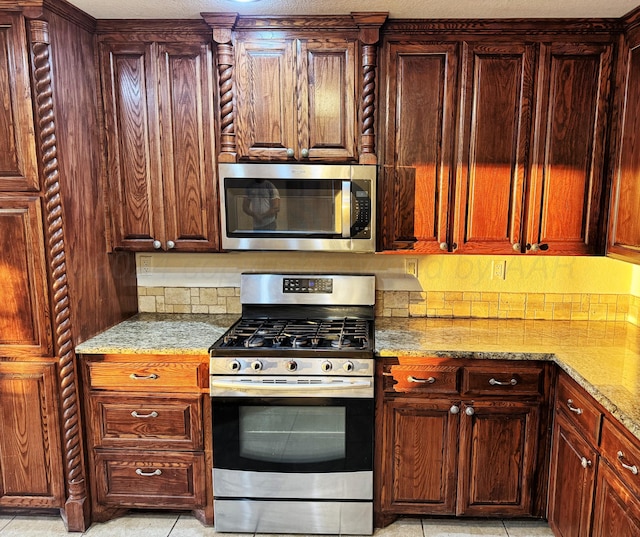 kitchen featuring tasteful backsplash, light stone counters, light tile patterned floors, and stainless steel appliances