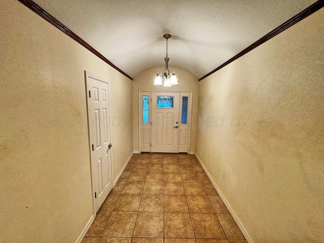 doorway to outside featuring an inviting chandelier, dark tile patterned floors, a textured ceiling, lofted ceiling, and ornamental molding