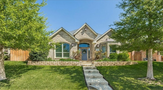 french country inspired facade with fence, a front lawn, and brick siding