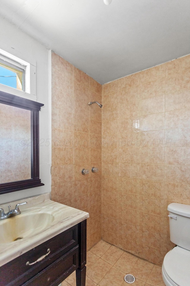 bathroom with toilet, vanity, tile patterned flooring, and a tile shower