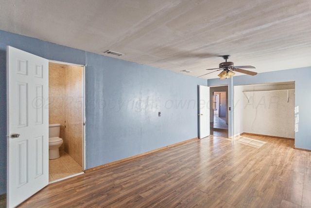 unfurnished bedroom featuring ceiling fan, hardwood / wood-style flooring, and ensuite bath