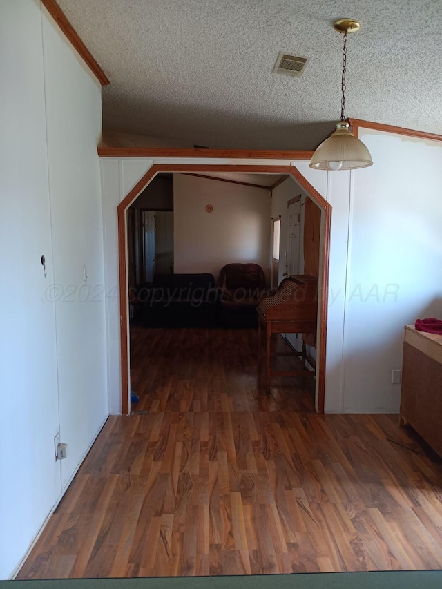 hall with a textured ceiling, crown molding, vaulted ceiling, and dark hardwood / wood-style floors