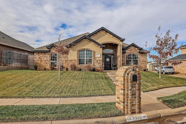 view of front of property featuring brick siding, fence, and a front lawn