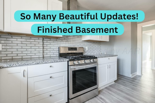 kitchen featuring tasteful backsplash, stainless steel range with gas stovetop, white cabinets, and light stone counters