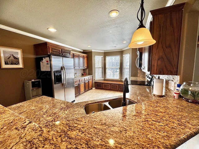 kitchen with a peninsula, a sink, ornamental molding, appliances with stainless steel finishes, and pendant lighting