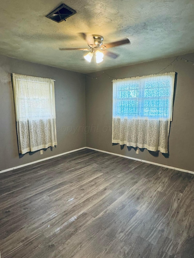 empty room featuring dark hardwood / wood-style flooring, a wealth of natural light, and ceiling fan