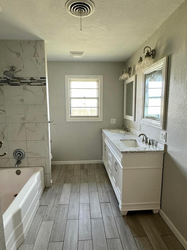 bathroom featuring vanity, wood-type flooring, a textured ceiling, and tiled shower / bath combo