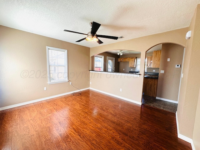 1521 Fox Ave, Dumas, TX 79029 - unfurnished living room featuring a textured ceiling, wood finished floors, a ceiling fan, healthy amount of natural light, and a textured wall