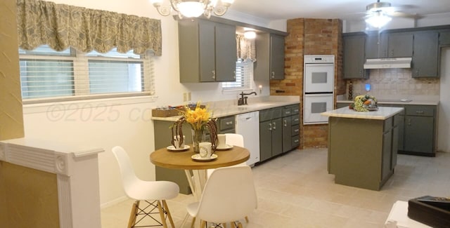 706 Mills Ave, Dumas, TX 79029 - kitchen with white appliances, under cabinet range hood, light countertops, backsplash, and a center island