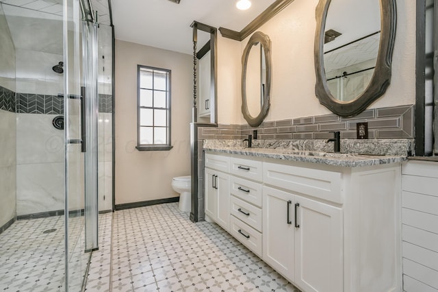 bathroom featuring vanity, toilet, a shower with shower door, and decorative backsplash