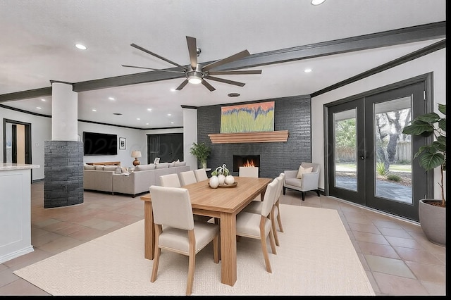 tiled dining space featuring french doors, ceiling fan, ornamental molding, and a brick fireplace