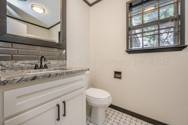 bathroom with ornamental molding, vanity, and toilet