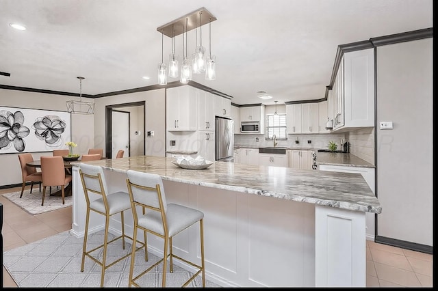 kitchen with sink, crown molding, appliances with stainless steel finishes, white cabinetry, and backsplash