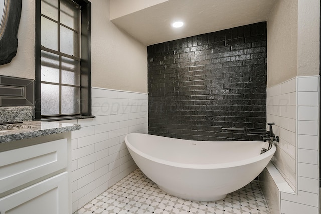 bathroom with vanity, tile walls, and a tub