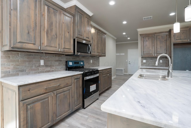 kitchen featuring light stone counters, stainless steel appliances, a sink, visible vents, and crown molding
