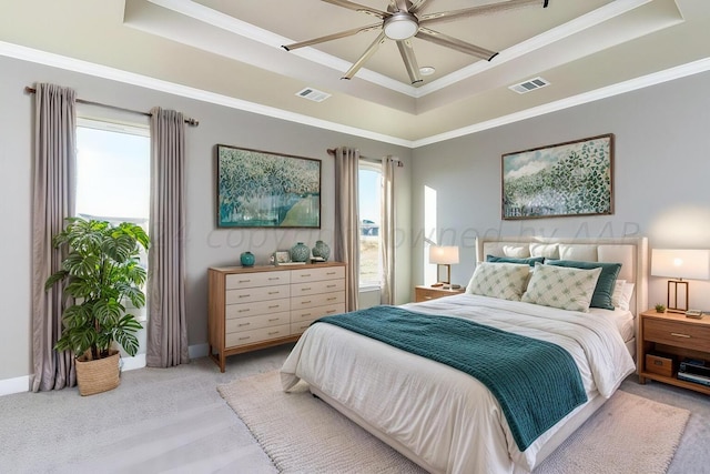 bedroom with visible vents, multiple windows, and a tray ceiling