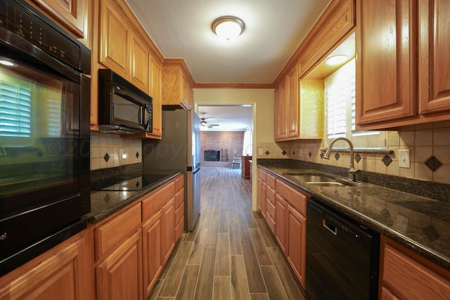 kitchen featuring sink, dark wood-type flooring, dark stone countertops, crown molding, and black appliances