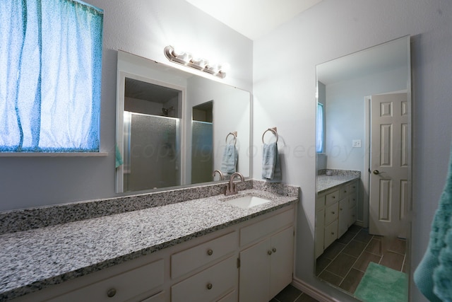 bathroom with tile patterned floors, vanity, and a shower with door