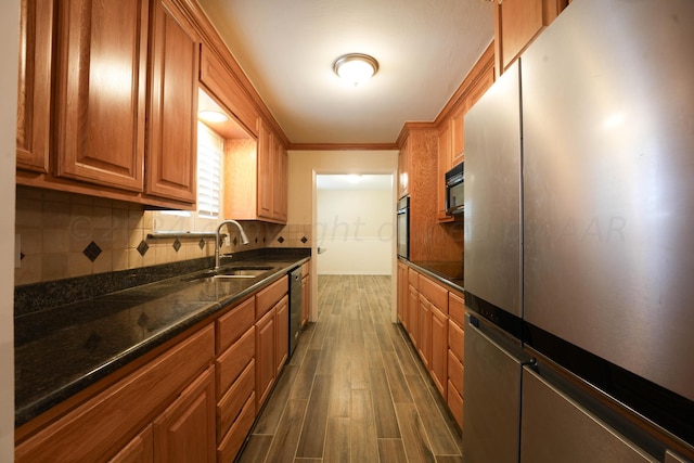 kitchen with dark stone counters, stainless steel appliances, crown molding, sink, and dark hardwood / wood-style floors