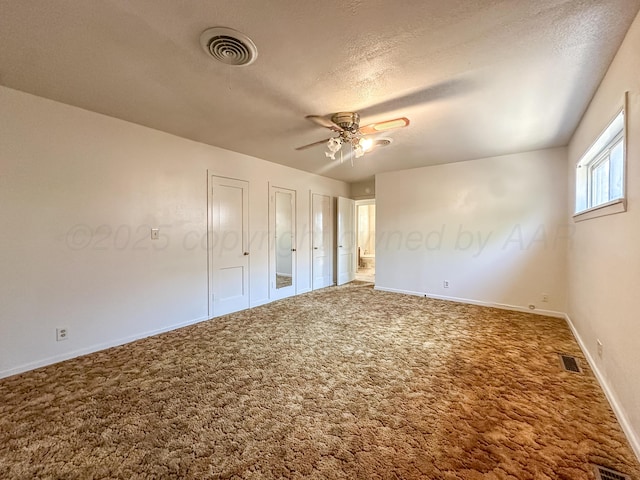 1705 Takewell St, Borger, TX 79007 - unfurnished bedroom featuring carpet floors, baseboards, a ceiling fan, a textured ceiling, and multiple closets