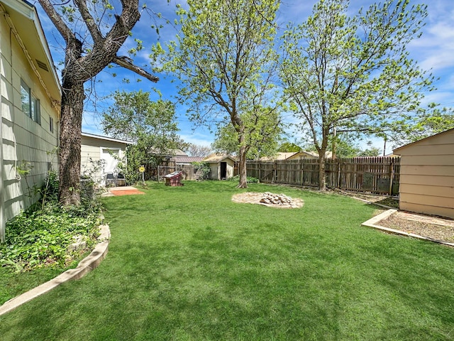 view of yard featuring an outdoor structure, a fenced backyard, and a storage unit