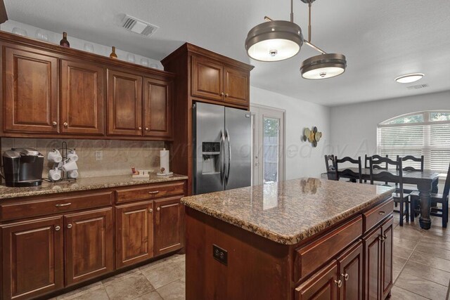 905 Red Deer Ln, White Deer, TX 79097 - kitchen featuring stainless steel fridge, backsplash, light tile patterned floors, stone countertops, and a center island