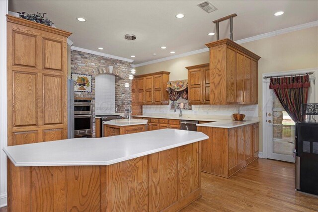 3511 Kensington Pl, Amarillo, TX 79121 - kitchen with appliances with stainless steel finishes, a kitchen island with sink, tasteful backsplash, brown cabinets, and light wood-style floors