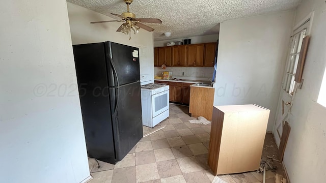 kitchen featuring a kitchen island, a ceiling fan, brown cabinets, freestanding refrigerator, and white range with gas cooktop