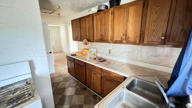 kitchen featuring brown cabinets, tile patterned floors, a sink, and light countertops