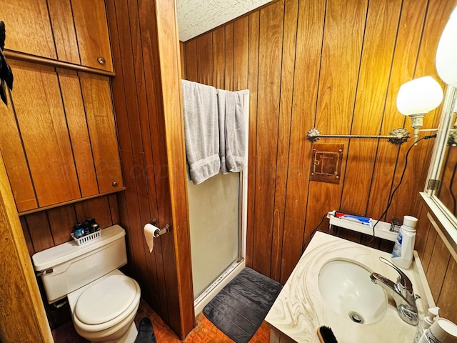 bathroom featuring wood walls, a shower stall, toilet, and vanity