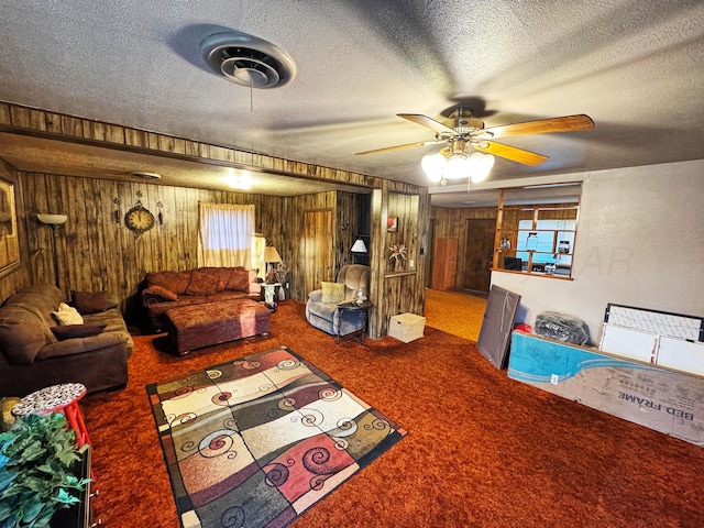 unfurnished living room featuring wooden walls, carpet, ceiling fan, and a textured ceiling