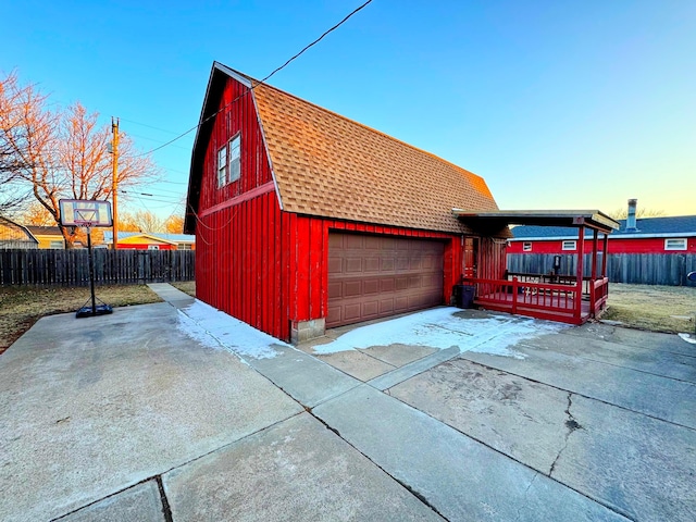 view of property exterior with an attached garage, a shingled roof, fence, and a gambrel roof