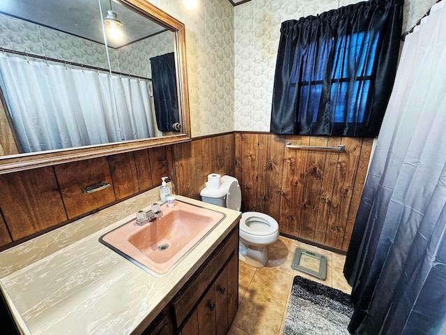 bathroom featuring wallpapered walls, toilet, a wainscoted wall, vanity, and wood walls