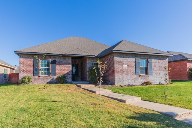 ranch-style house with roof with shingles, a front yard, and brick siding