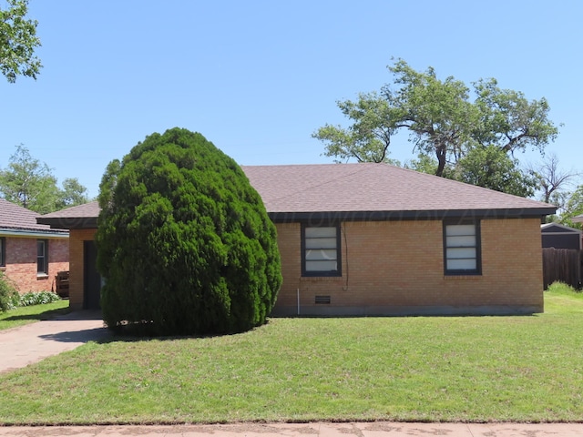 view of front of home featuring brick siding, a front yard, a shingled roof, and driveway