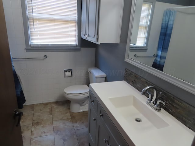 full bath with toilet, vanity, a shower with curtain, tile walls, and tile patterned flooring